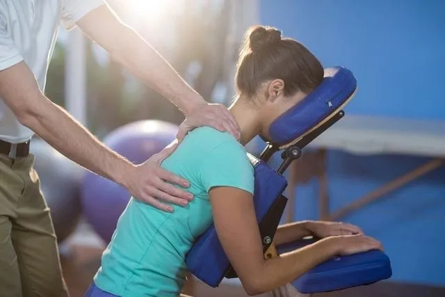 A person is holding on to the back of a chair.